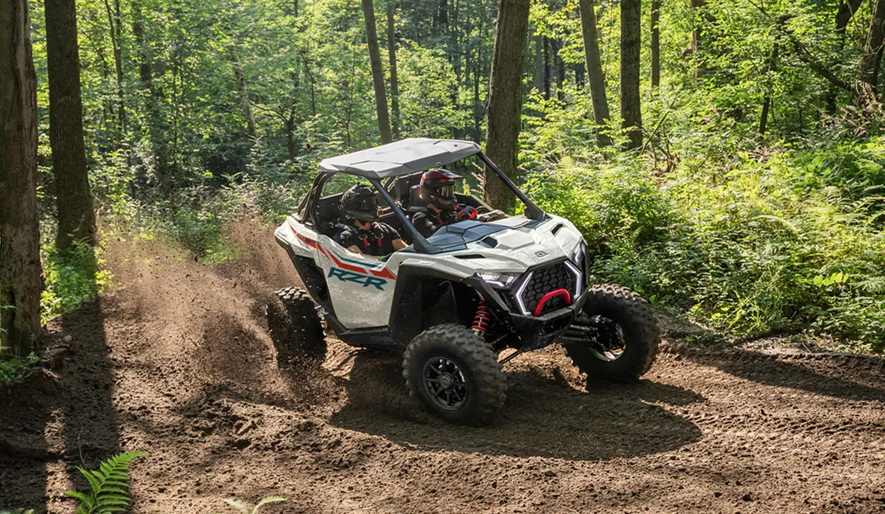 A Polaris RZR Pro XP side-by-side cruising on a forest trail.