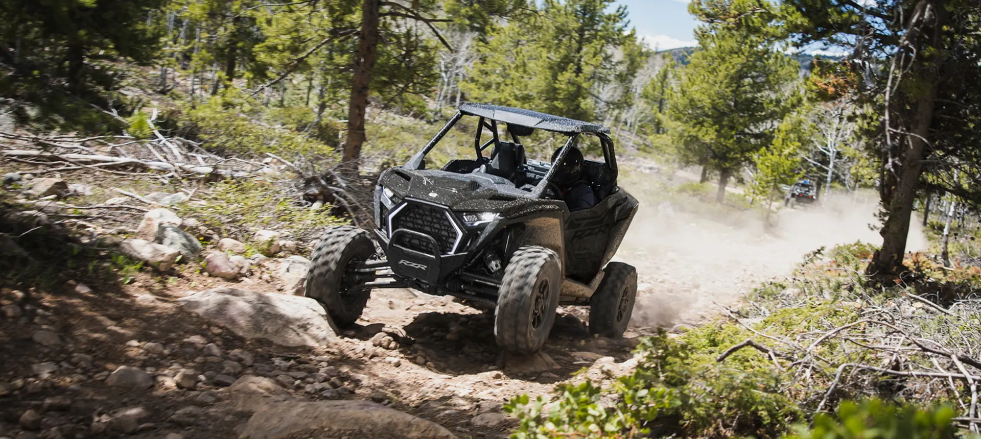 Front end view of a Polaris RZR Pro XP side-by-side driving on a trail.