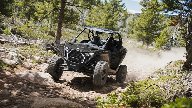 Front end view of a Polaris RZR Pro XP side-by-side driving on a trail.