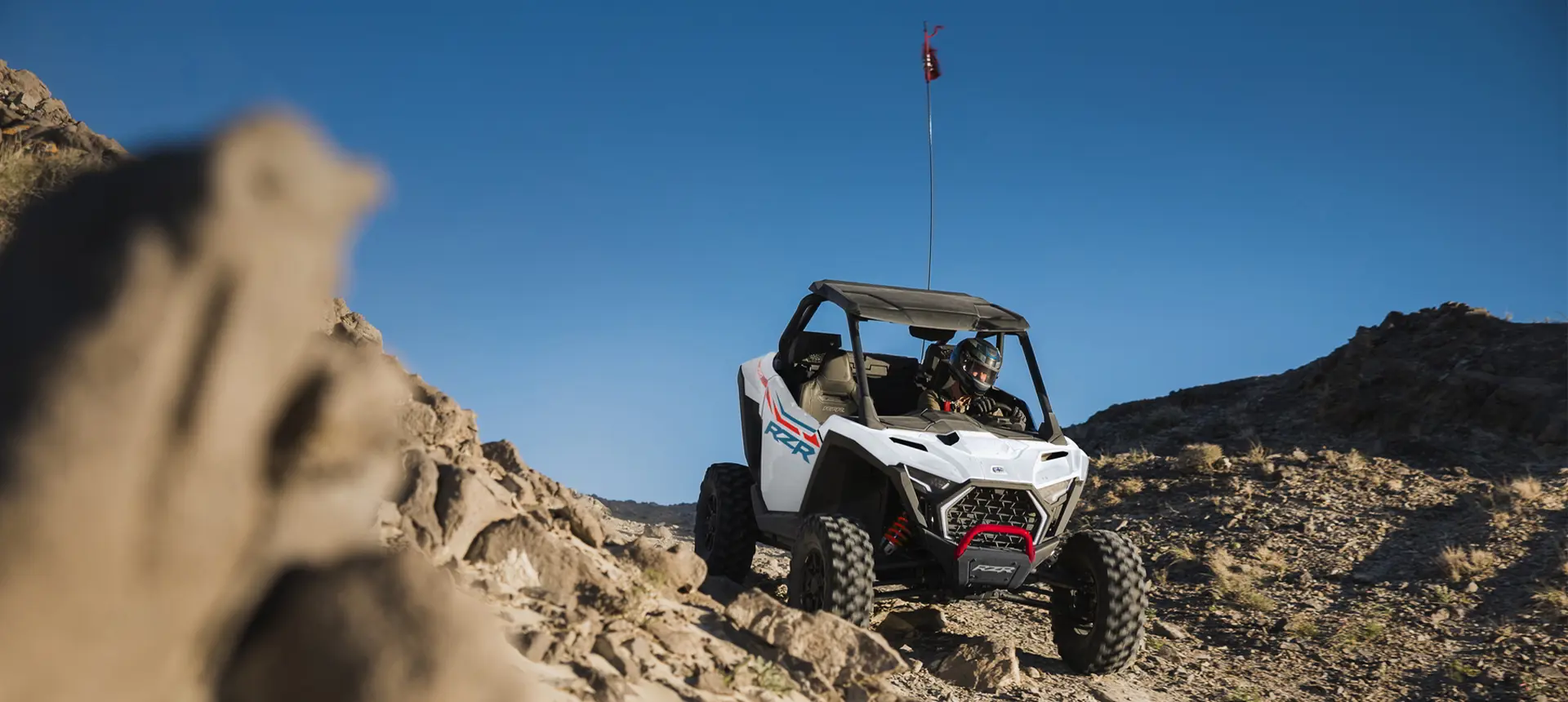 A Polaris RZR Pro XP side-by-side driving over rocky terrain in the desert.