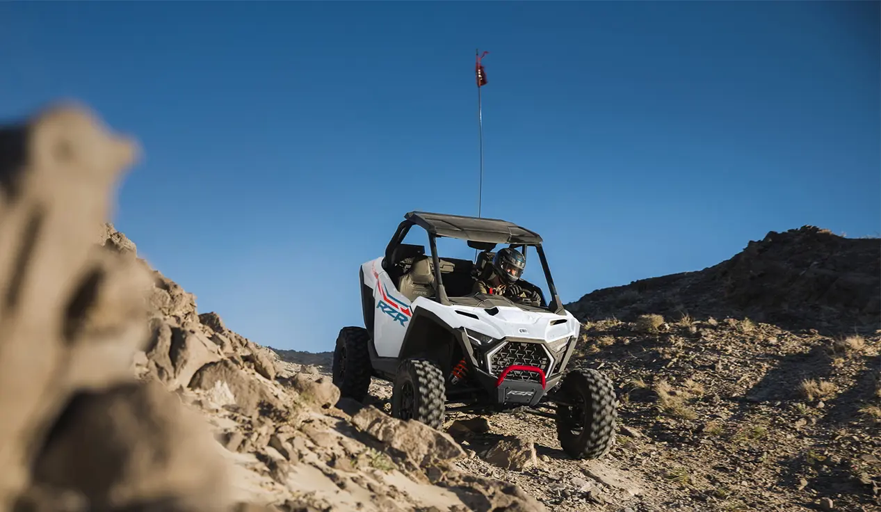 A Polaris RZR Pro XP side-by-side driving over rocky terrain in the desert.