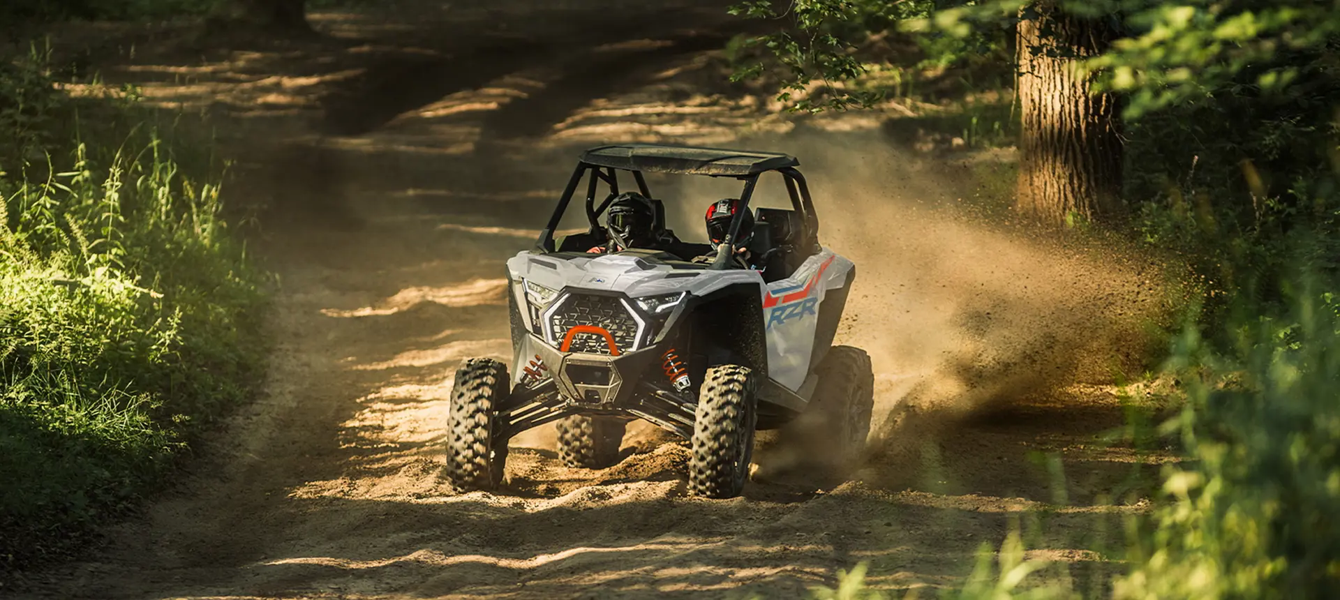 A Polaris RZR Pro XP side-by-side driving out of the forest while trail riding.