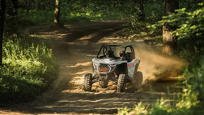 A Polaris RZR Pro XP side-by-side driving out of the forest while trail riding.