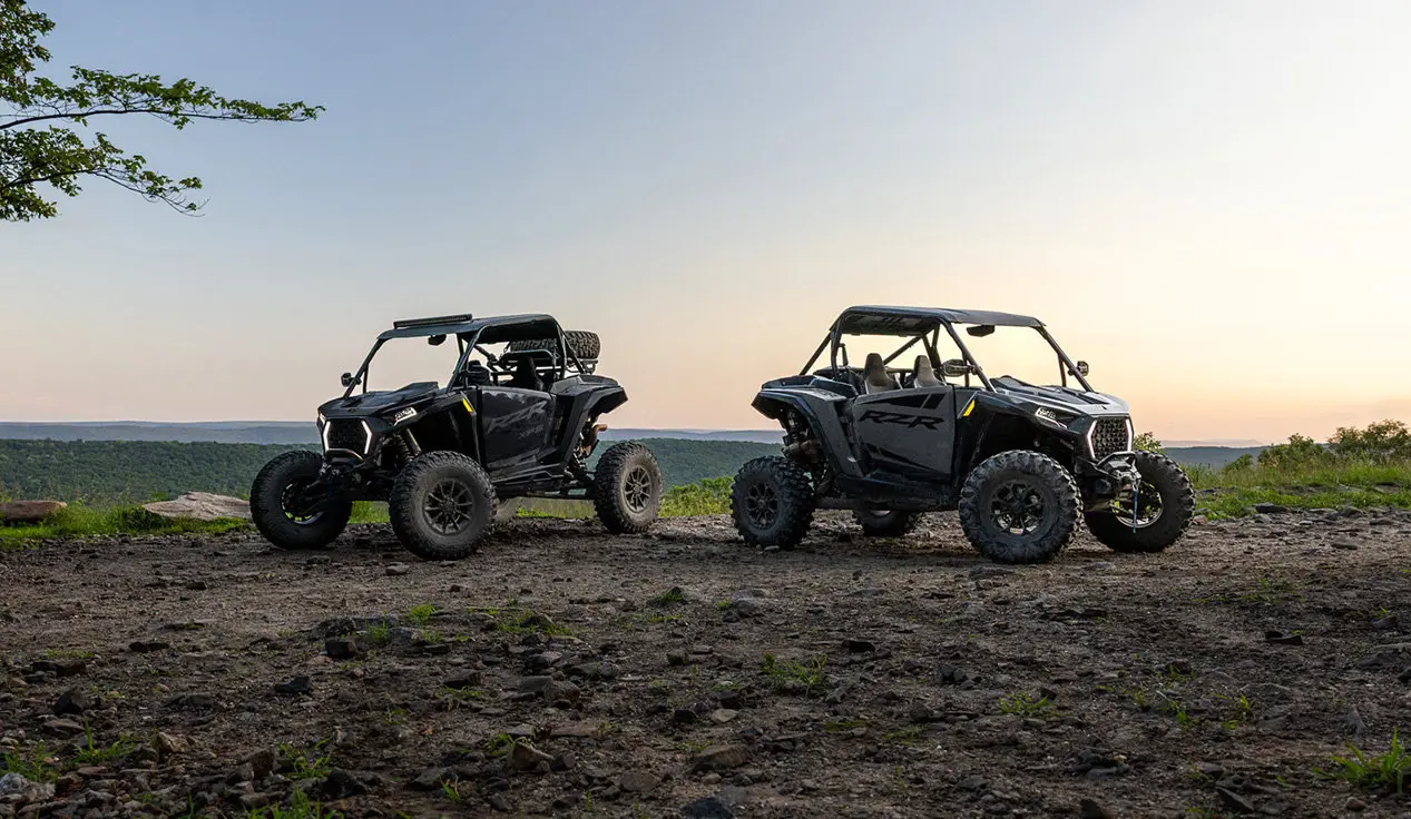 A Polaris RZR XP and RZR XP S side-by-side parked on a ridge.