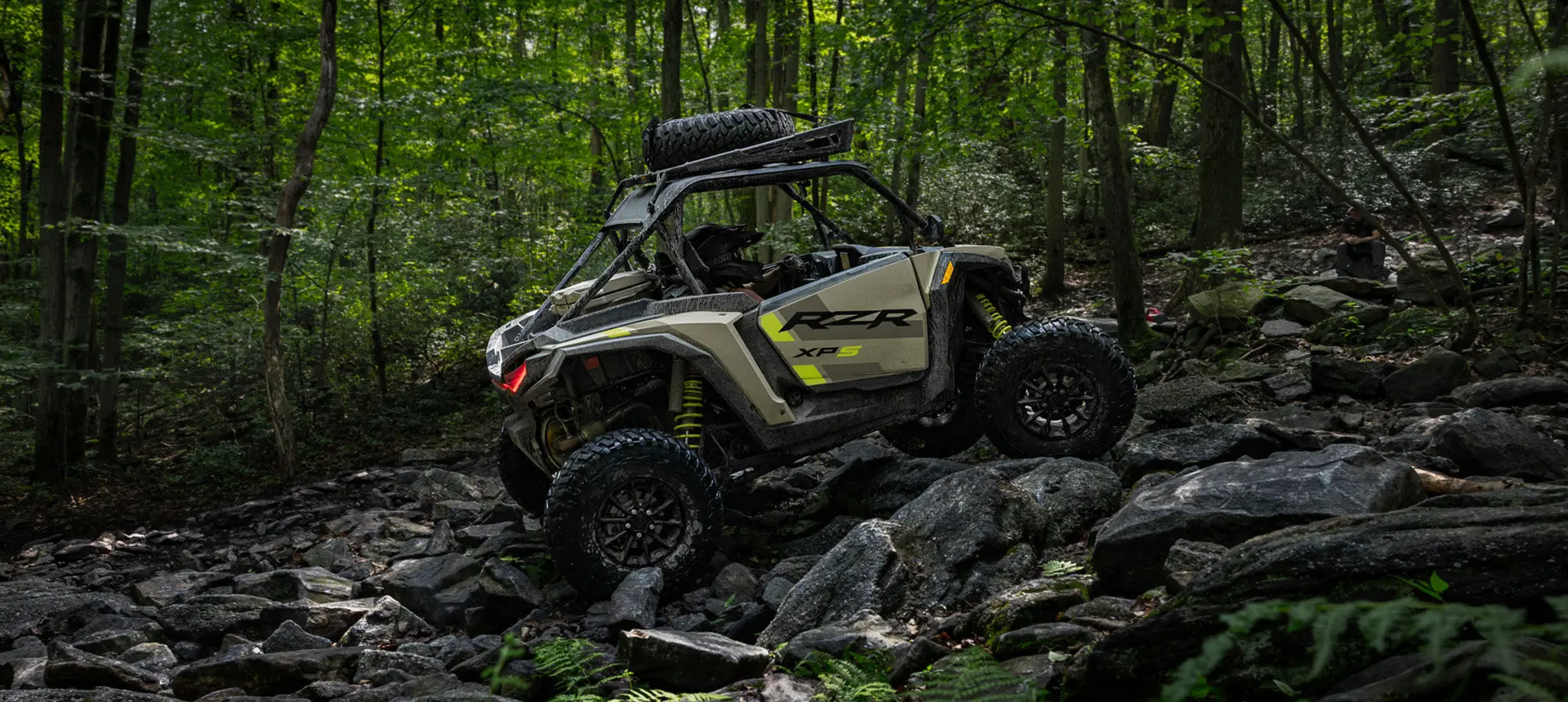 Side profile of a RZR XP side-by-side climbing over rocky terrain.