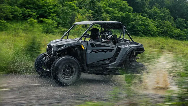 Side profile of a RZR XP side-by-side cruising down a forest trail.