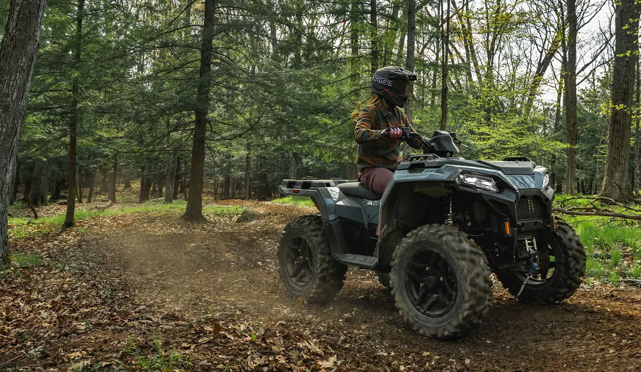 Rider on a Polaris Sportsman 500 ATV cruising on a trail.