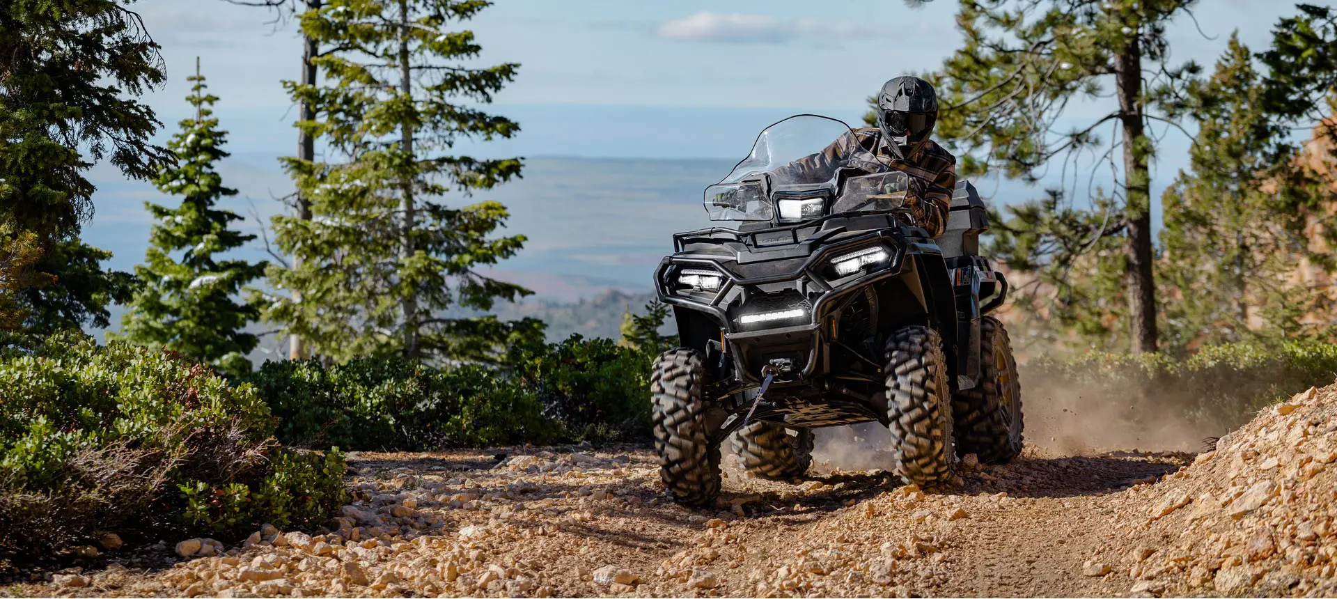 Rider on a Polaris Sportsman 600 ATV cruising on a trail.