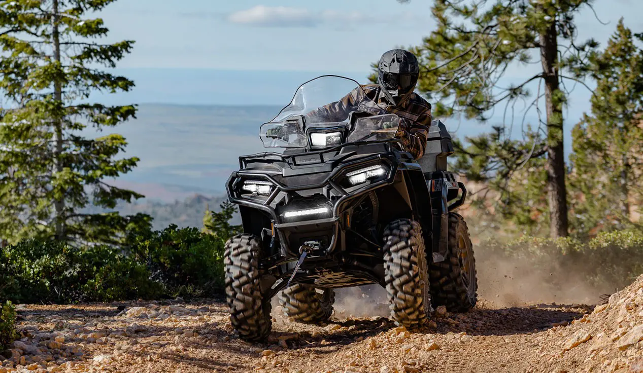 Rider on a Polaris Sportsman 600 ATV cruising on a trail.