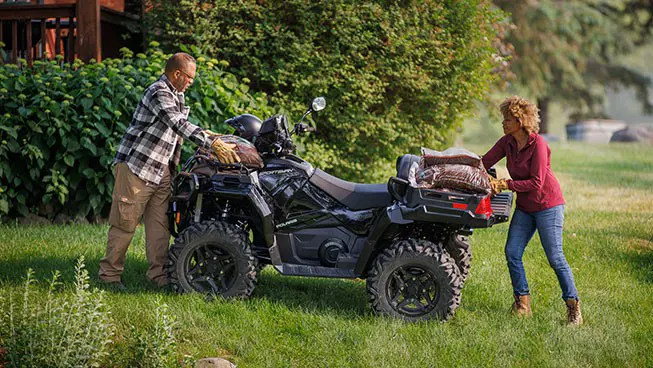 2 people unloading mulch from the cargo racks on their Polaris Sportsman 600 ATV.