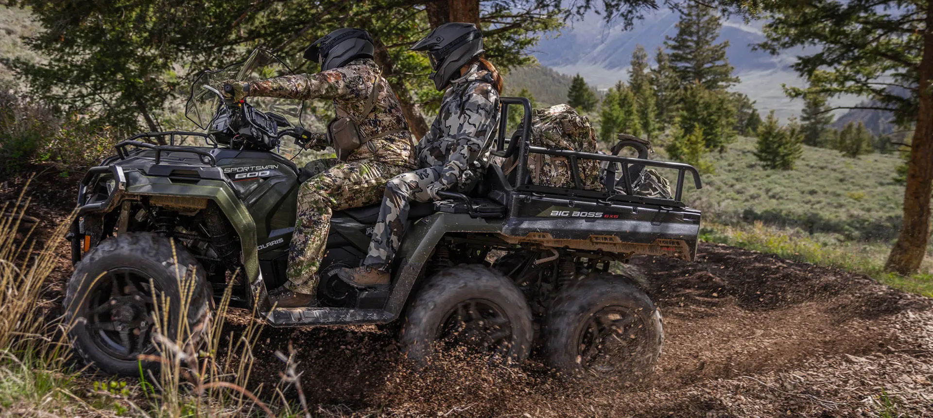 Two hunters riding on a Polaris Sportsman 6x6 600 ATV through mud.