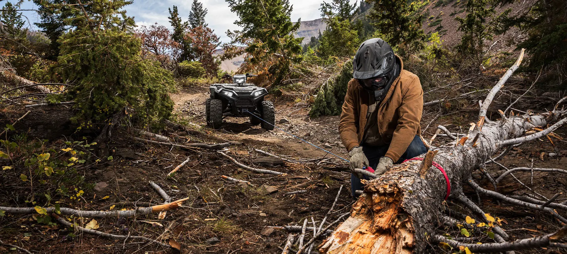 A person using the winch from their Polaris Sportsman XP 1000 ATV to move a log off the trail.