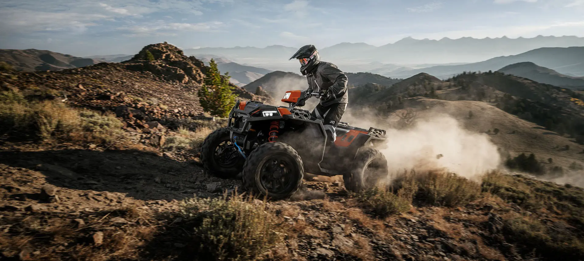 Side profile of a rider on a Polaris Sportsman XP 1000 S ATV ascending a hill.