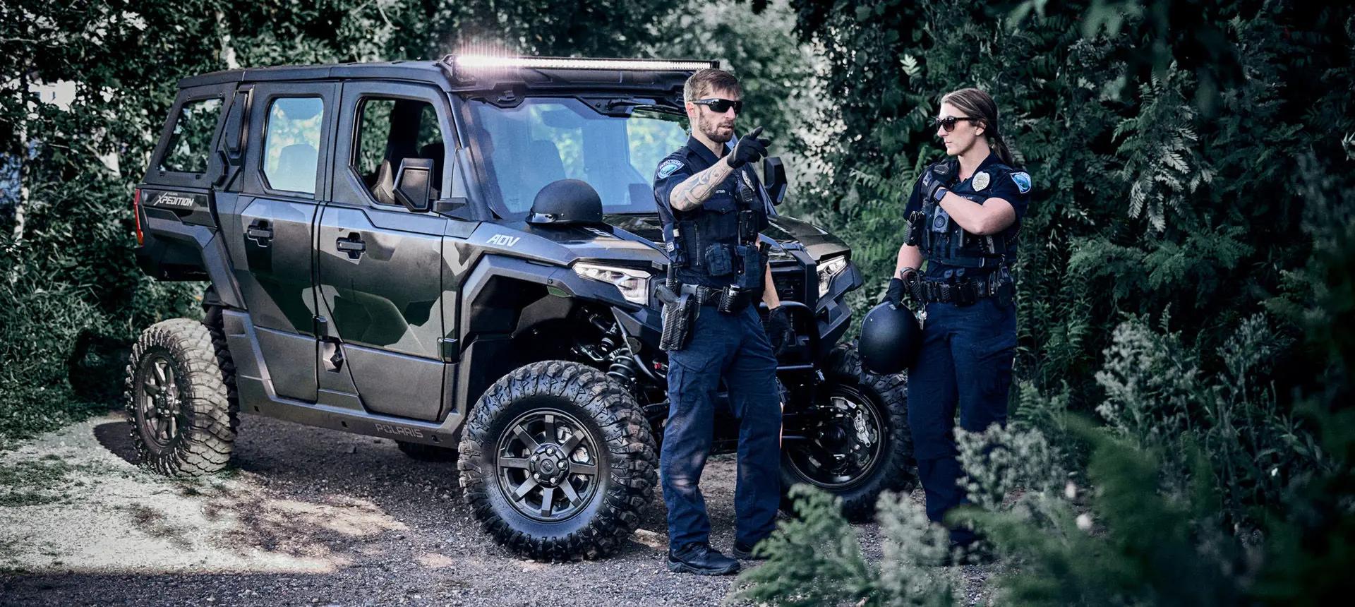 2 law enforcement officers near a Matte Super Graphite Polaris XPEDITON ADV 5 performance side-by-side.