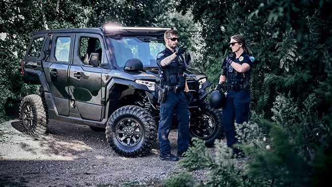 2 law enforcement officers near a Matte Super Graphite Polaris XPEDITON ADV 5 performance side-by-side.