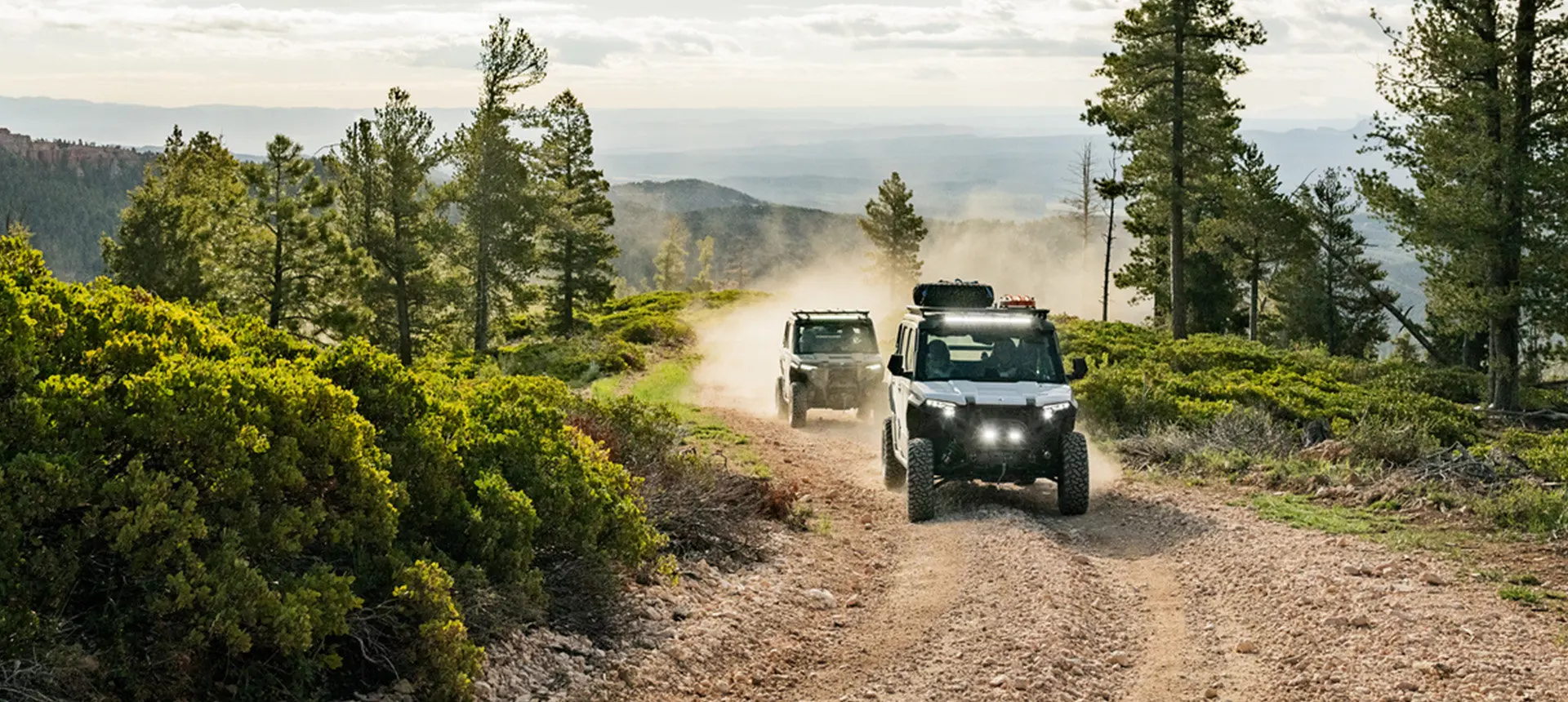 Two Polaris XPEDITION XP NorthStar side-by-side cruising on a dirt road.
