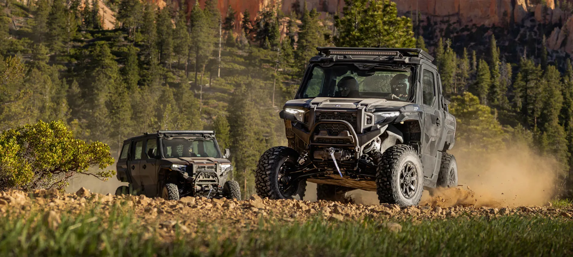 2 Polaris XPEDITION XP NorthStar side-by-side driving on a rocky trail.
