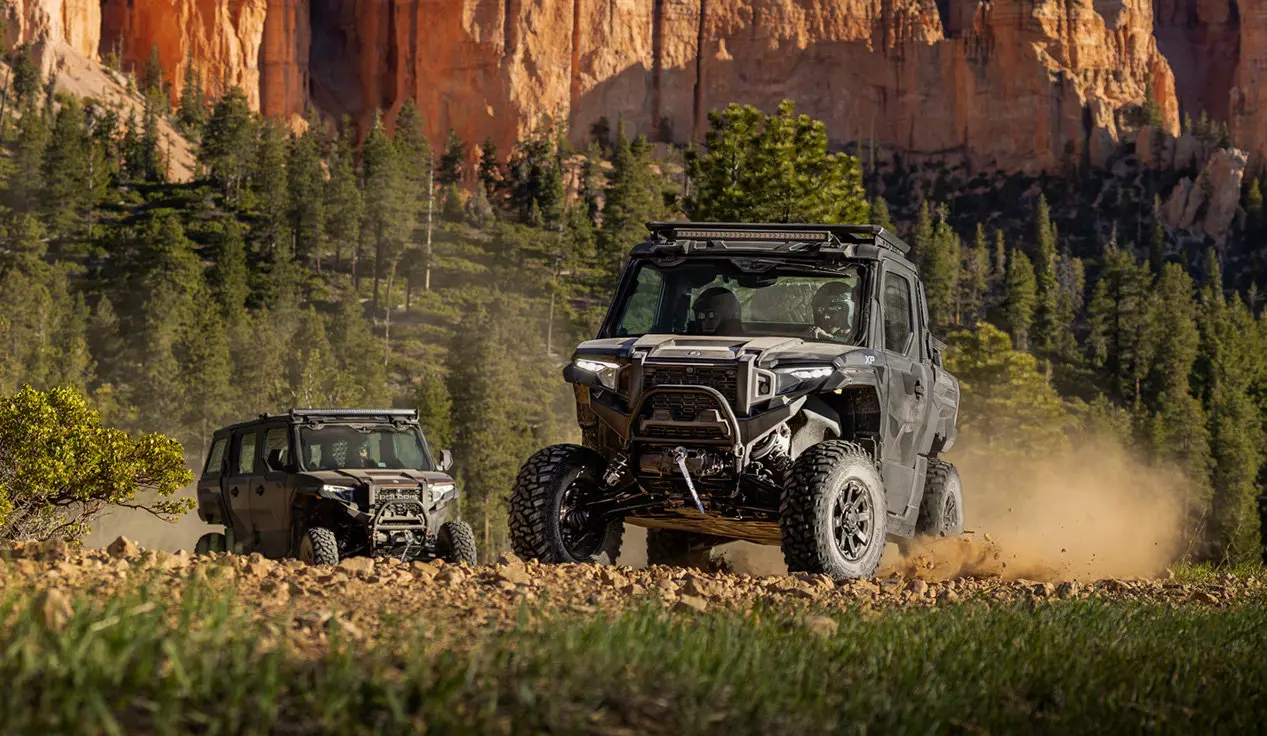 2 Polaris XPEDITION XP NorthStar side-by-side driving on a rocky trail.