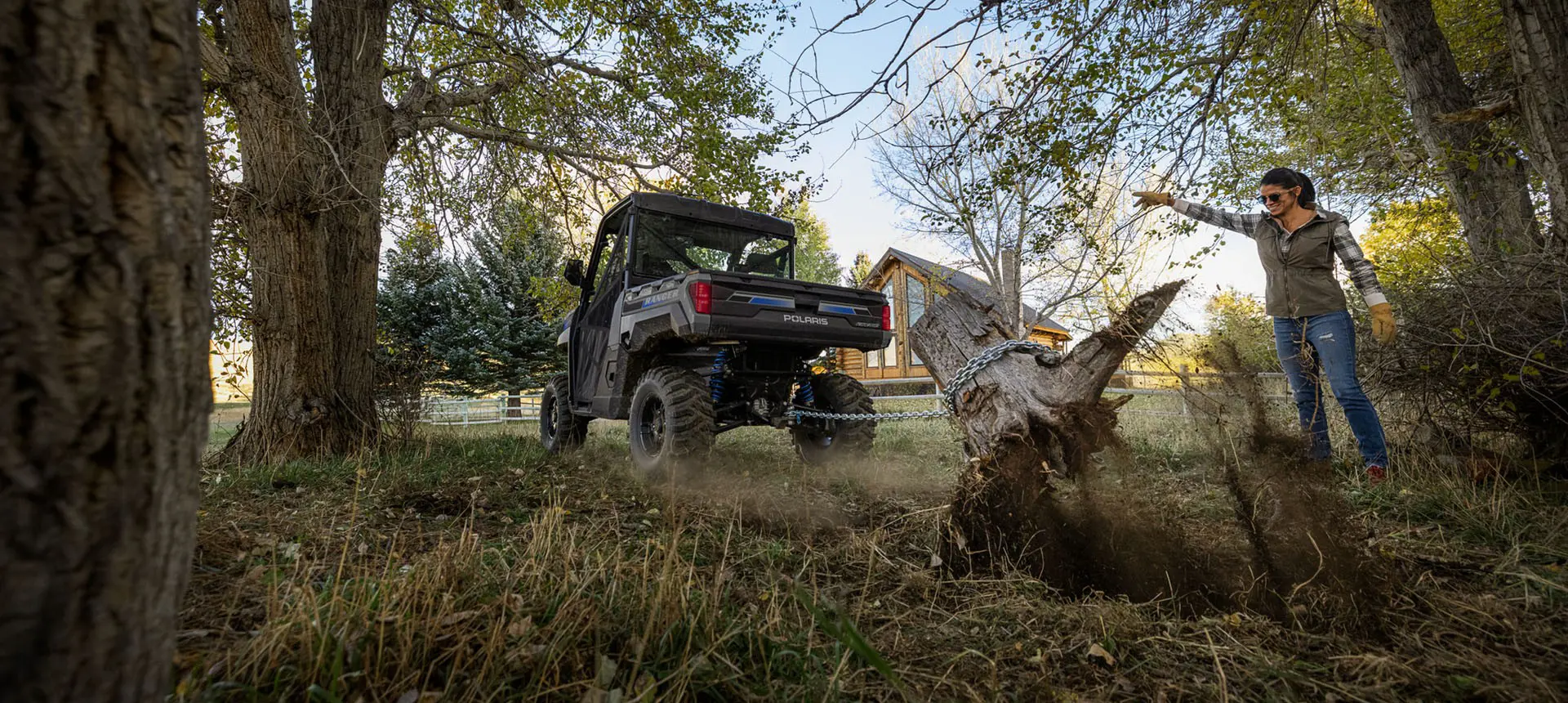 A person using a Polaris RANGER XP Kinetic electric UTV pull out a stump in their yard.