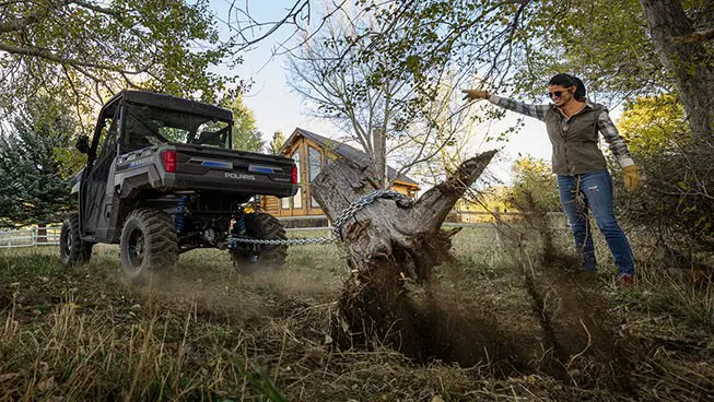 A person using a Polaris RANGER XP Kinetic electric UTV pull out a stump in their yard.