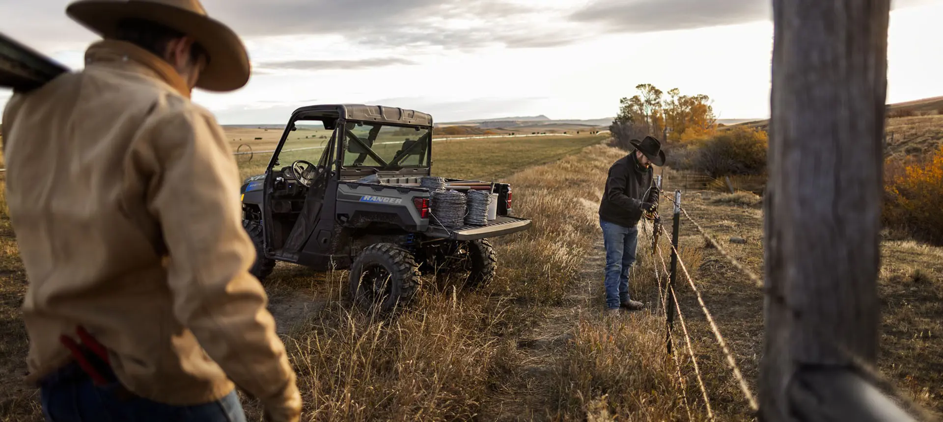 2 ranchers hauling barbed wire in a Polaris RANGER XP Kinetic electric UTV to assist with fence repairs.