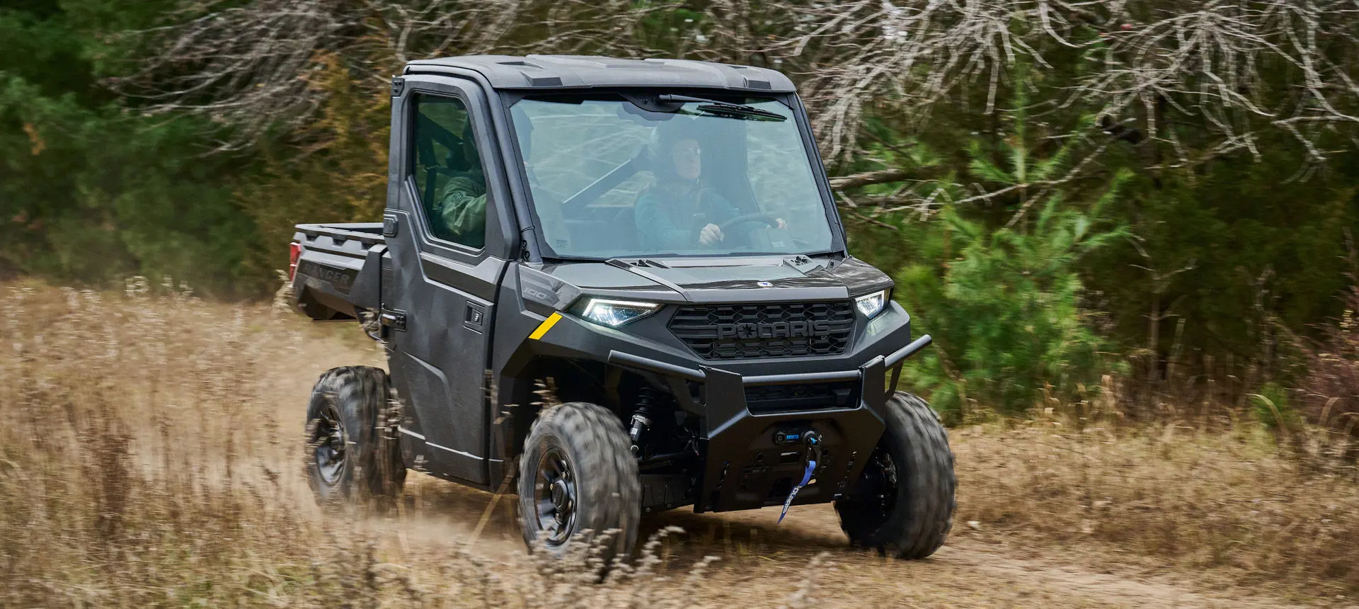 A Polaris RANGER 1000 Cab UTV driving through a field.