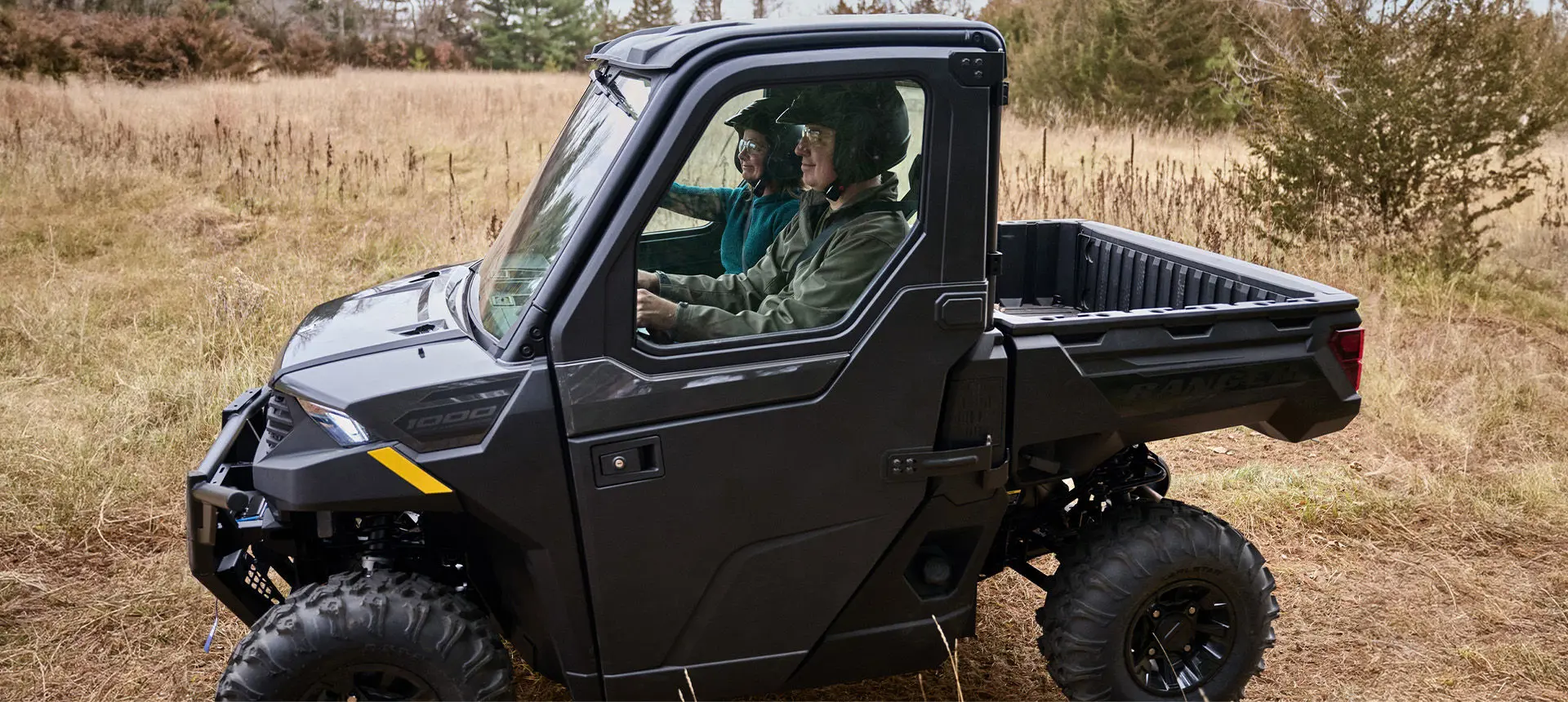 Side profile of a Polaris RANGER XP 1000 Cab UTV in a field.