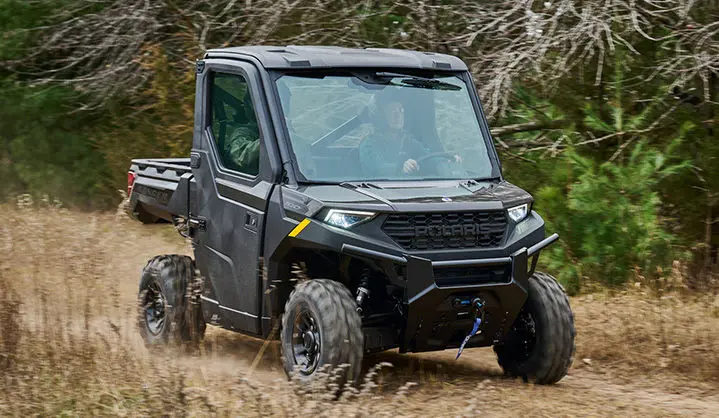A Polaris RANGER 1000 Cab UTV driving through a field.