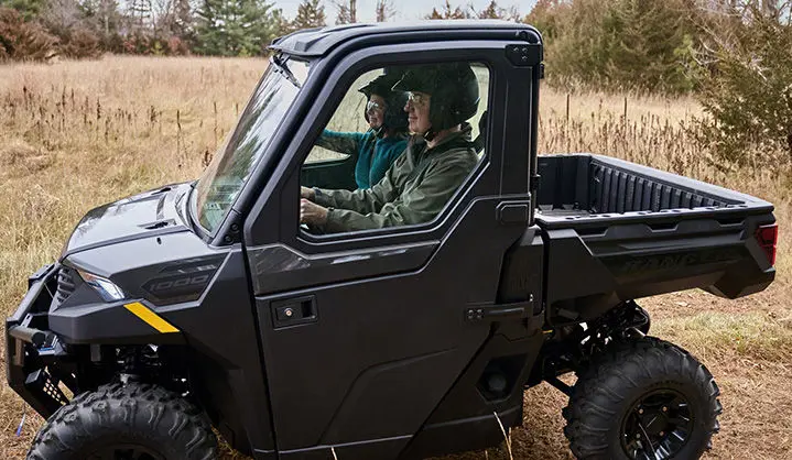 Side profile of a Polaris RANGER XP 1000 Cab UTV in a field.