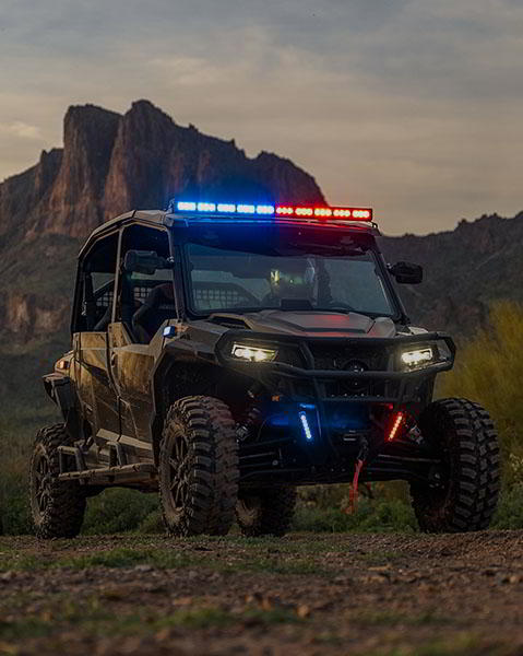An officer driving a police side by side with flashing red and blue lights.