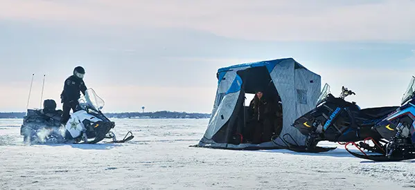 DNR Officer riding on a Polaris Government-issued snowmobile to check on someone ice fishing.