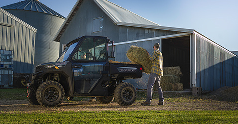 A man loading hay in the back of a Ranger 1000