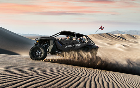 Side views of a Polaris RZR racing through the desert