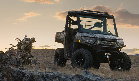 A hunter walking towards his Polaris Ranger vehicle before dusk
