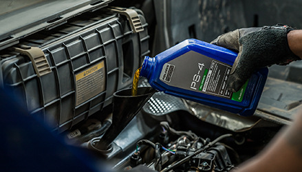 closeup of an oil bottle being poured into a motor