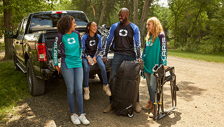 a group of people wearing Polaris apparel clothing, chatting sitting on the back of a pickup truck