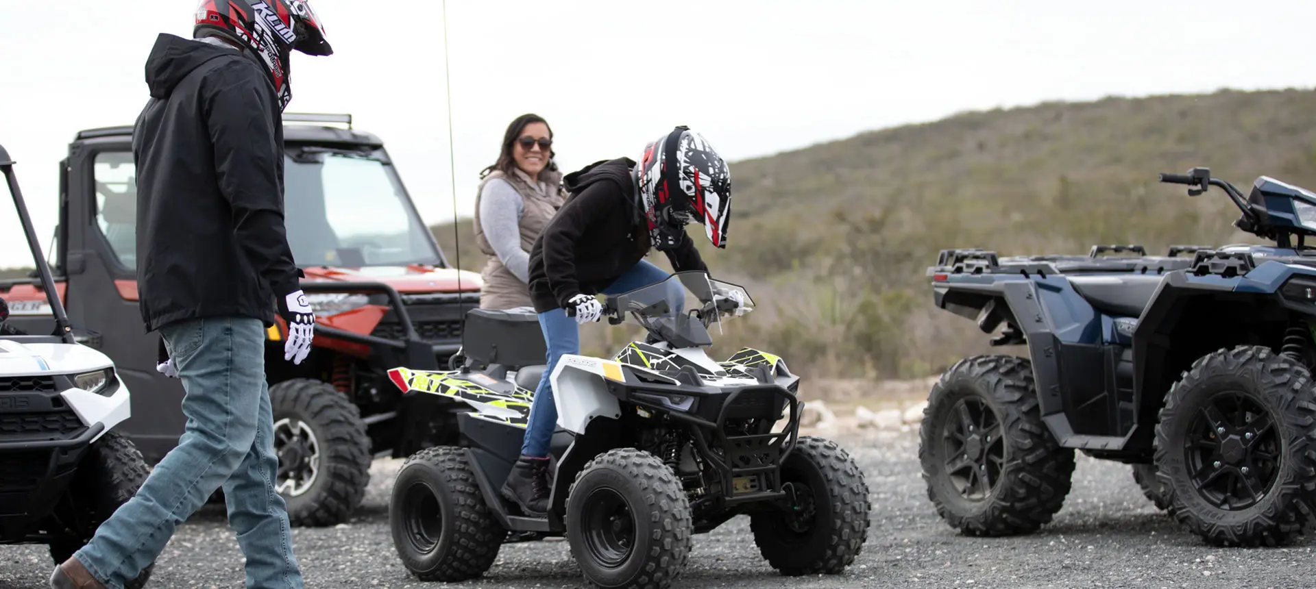 Boy getting seated on a polaris outlaw 70 youth atv