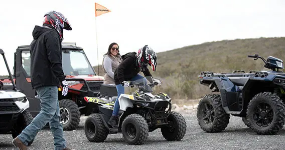 Boy getting seated on a polaris outlaw 70 youth atv