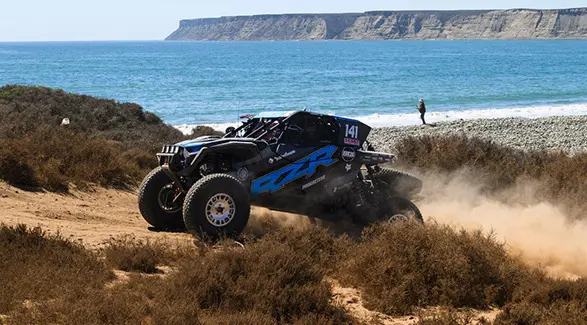 Profil latéral d’un côte à côte Polaris RZR Pro XP 2025 roulant sur un sentier rocailleux.