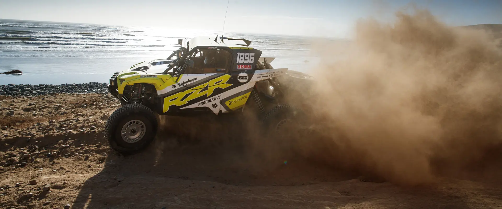 Côte à côte Polaris RZR Pro XP 2025 projetant du gravier sur un sentier poussiéreux.