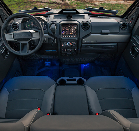 Interior de un vehículo Polaris XPEDITION NorthStar Edition con el logotipo “POLARIS” en el volante, iluminación ambiental azul y varios controles en la consola central.