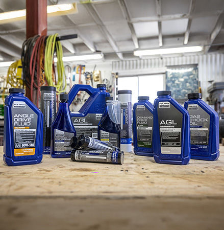 An oil change kit and a maintenance kit for Polaris off-road vehicles are placed on a wooden table.