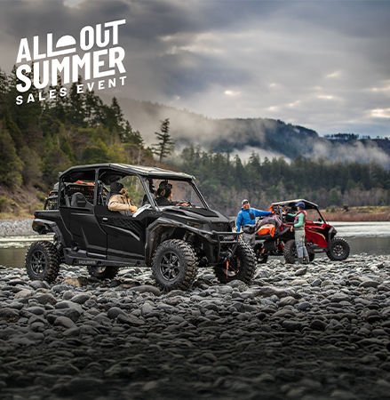 Two Polaris RZR XP off-road side-by-side vehicles parked on a rocky riverbed.