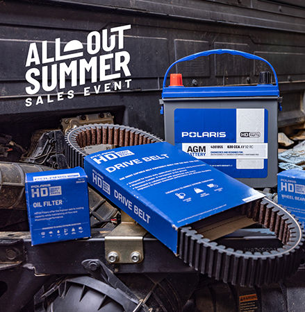 A collection of Polaris HD (Heavy Duty) off-road vehicle parts, featuring a large AGM battery, a drive belt unboxed, and blue boxes for an oil filter, wheel bearing, and brake pads.