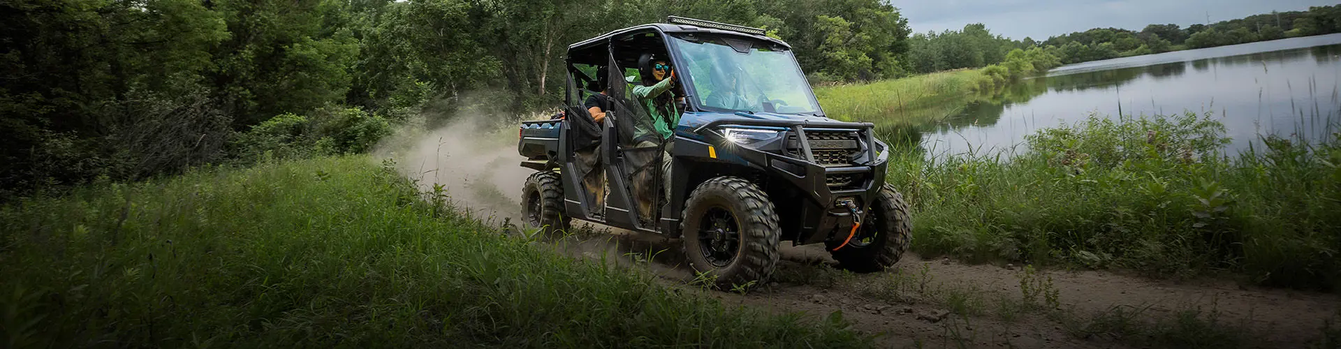 Riders in a Polaris RANGER driving down a dirt trail.