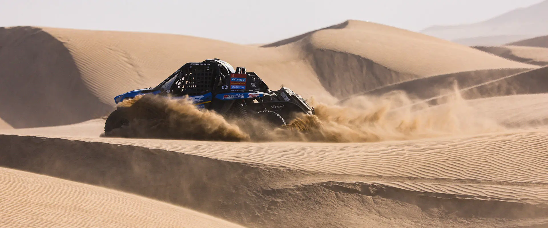 Dakar Rally RZR Pro R Factory driving through large sand dunes.