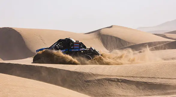Dakar Rally RZR Pro R Factory driving through large sand dunes.