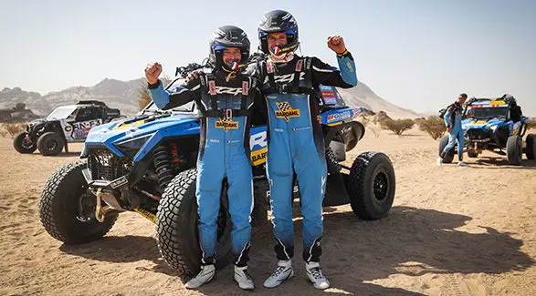 Brock Heger and Xavier de Soultrait are posing in front of their RZR Pro R Factory after winning one of the stages of the Dakar Rally.