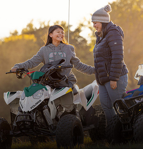 Kids and an adult on youth SXS, ATVs 4-wheelers in golden hour light.