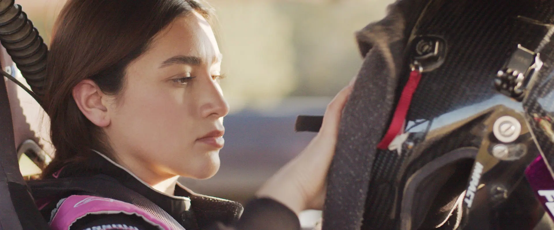 Fernanda Montiel inside her Polaris RZR SxS, putting on her helmet and preparing for a race.